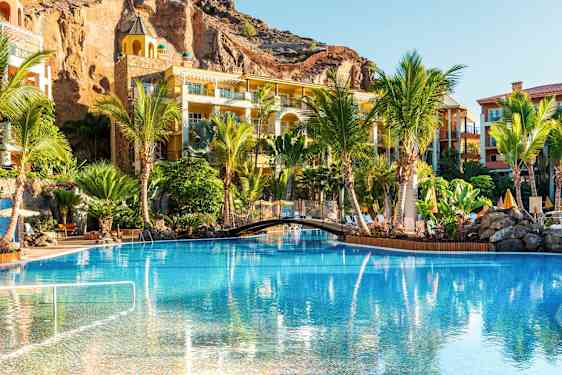 Et basseng omgitt av palmer og ferieboliger. (AI-generert tekst)