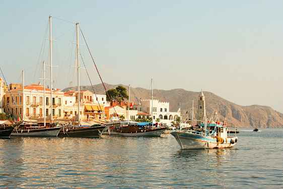 En havn med båter og bygninger, fjell ses i bakgrunnen. (AI-generert tekst)