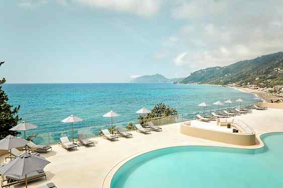 Utsikt over et basseng og havet med solsenger og parasoller på en terrasse. (AI-generert tekst)