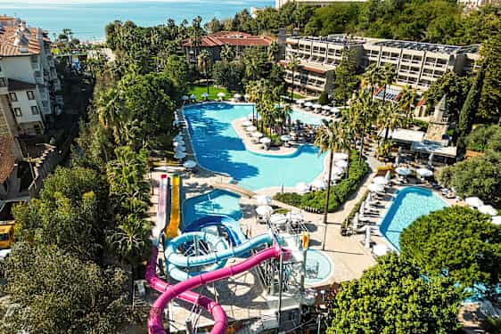 Utsikt over en resort med flere bassenger og vannsklier, omgitt av grøntområder. (AI-generert tekst)