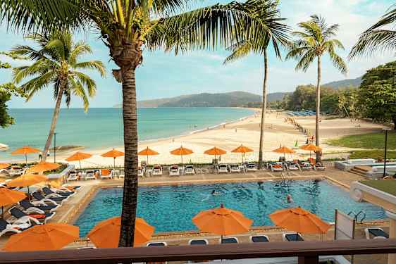 En strand med et basseng i forgrunnen, omgitt av solsenger og parasoller. (AI-generert tekst)