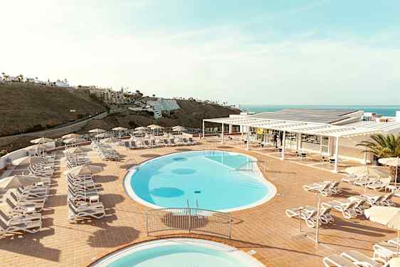Bassengområde med solsenger og parasoller på en terrasse med havutsikt. (AI-generert tekst)