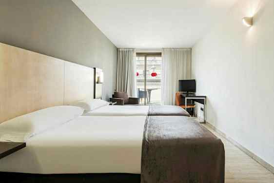 Et hotellrom med to enkeltsenger og et skrivebord ved siden av en balkong. (AI-generert tekst)
