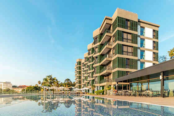 En moderne bygning ved et basseng med klar blå himmel. (AI-generert tekst)