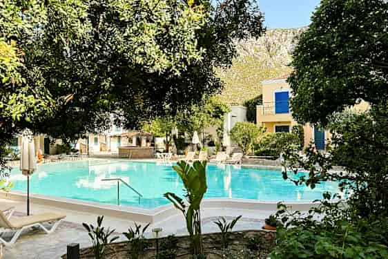 Bildet viser et basseng omgitt av trær og solsenger. (AI-generert tekst)