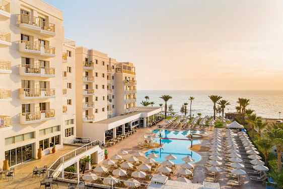 Hotell med balkonger, bassengområde og hav i bakgrunnen. (AI-generert tekst)