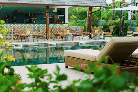 Bilde av et bassengområde med solsenger og en bar i bakgrunnen. (AI-generert tekst)