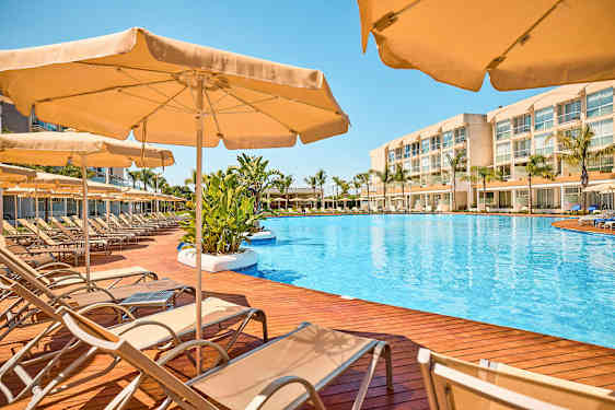 Bassengområde med solsenger og parasoller på en treterrasse. (AI-generert tekst)