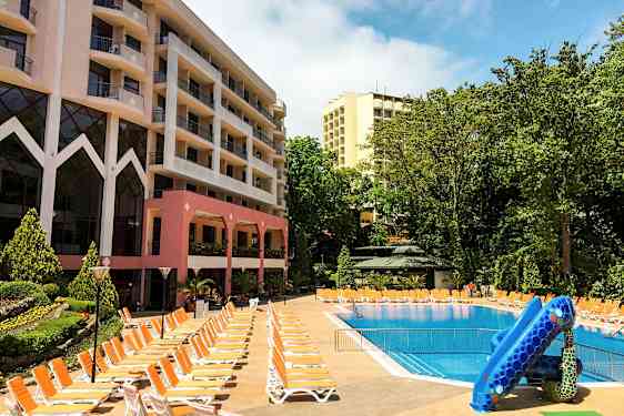 Hotellbyggninger ved et utendørs basseng med solsenger og vannsklie. (AI-generert tekst)