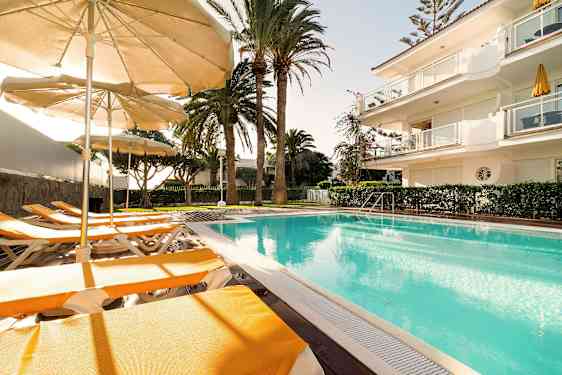 Utendørsbasseng med solsenger og parasoller i solfylt vær. (AI-generert tekst)