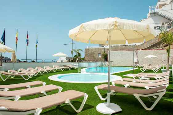 Utendørs bassengområde med solsenger og parasoller, omgitt av grønn plen. (AI-generert tekst)