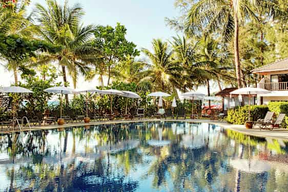 Utendørsbasseng omgitt av solsenger og parasoller, med palmer i bakgrunnen. (AI-generert tekst)