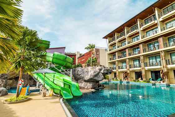 Hotellbasseng med grønne sklier og en bygning i bakgrunnen. (AI-generert tekst)