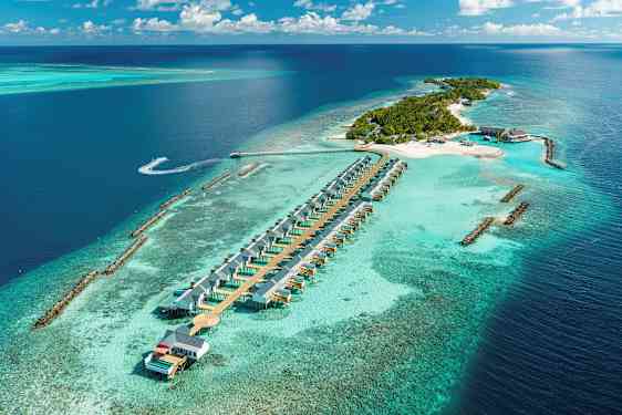 Luftfoto av en tropisk øy med strandvillaer i vannet og omkringliggende turkis hav. (AI-generert tekst)