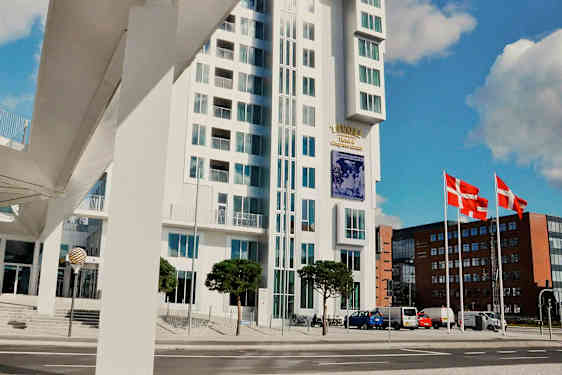 Moderne bygning med glassfasade ved siden av en gate. Danmarks flagg er synlige på flaggstenger. (AI-generert tekst)