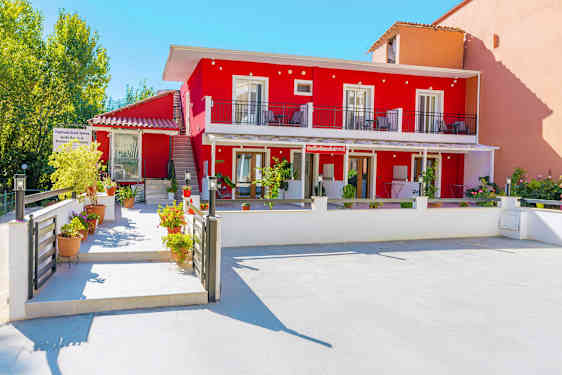 Bilde som viser en rød bygning med balkonger og blomsterpotter i forgrunnen. (AI-generert tekst)