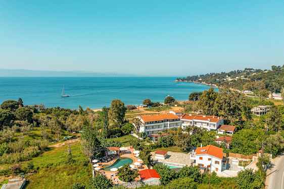 Landskapsbilde som viser bygninger med røde tak nær en kyst med havutsikt. (AI-generert tekst)