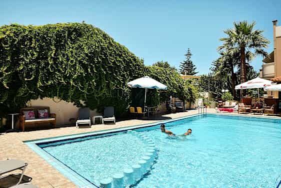 Et utendørs svømmebasseng omgitt av grøntområder og solsenger. (AI-generert tekst)