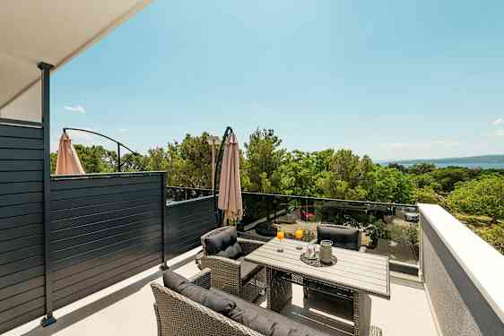 En møblert terrasse med utsikt over natur og hav. (AI-generert tekst)