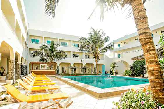 Utendørsområde med basseng, solsenger og omkringliggende bygninger. (AI-generert tekst)