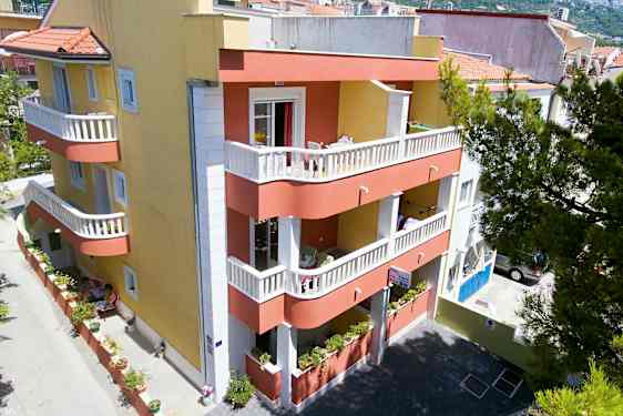 En bygning med gul og rød fasade, balkonger og en liten indre gårdsplass. (AI-generert tekst)