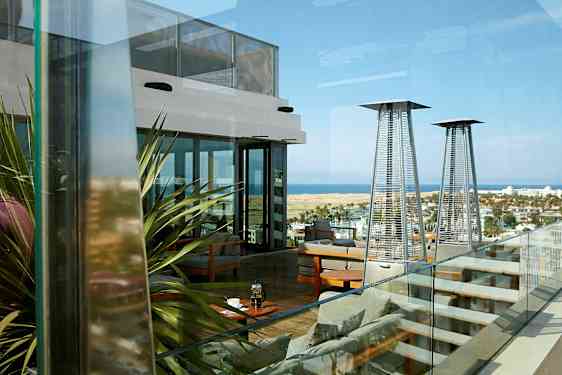 En takterrasse med sitteplasser, varmelamper og utsikt over landskapet og havet. (AI-generert tekst)