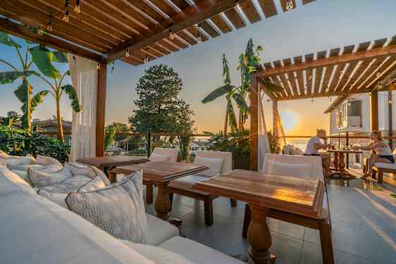 Uteområde med trepergola, sitteplasser og utsikt ved solnedgang. (AI-generert tekst)