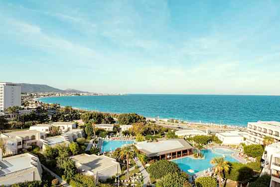 Utsikt over hotellområdet med bassenger og havet i bakgrunnen. (AI-generert tekst)