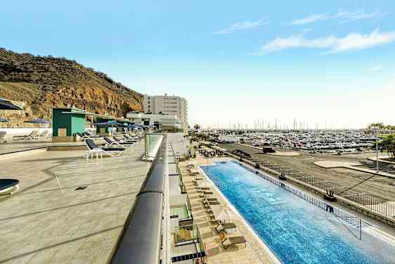 Bassengområde med solsenger ved siden av en marina og en fjellside. (AI-generert tekst)