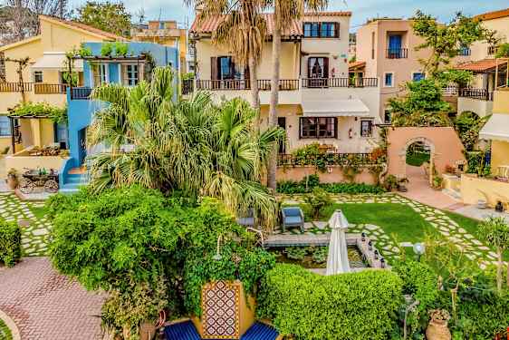 Sjarmerende hus med fargerike fasader omgitt av grøntområder og blomster. (AI-generert tekst)