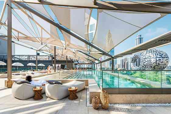 Et moderne utendørs basseng med sitteplasser og utsikt over byens skyline. (AI-generert tekst)