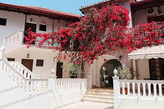 En bygning med hvite vegger og røde blomster som klatrer på fasaden. (AI-generert tekst)