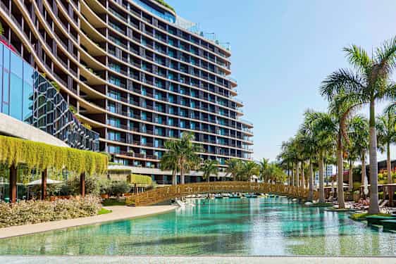 Bilde av en moderne bygning med glassfasade ved et basseng omgitt av palmer. (AI-generert tekst)