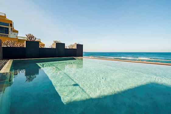 Et infinitybasseng med utsikt over havet under en klar himmel. (AI-generert tekst)