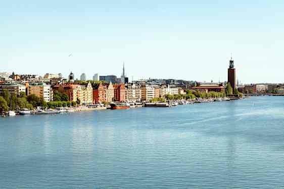 Bymiljø ved et vannspeil med bygninger og båter i forgrunnen. (AI-generert tekst)