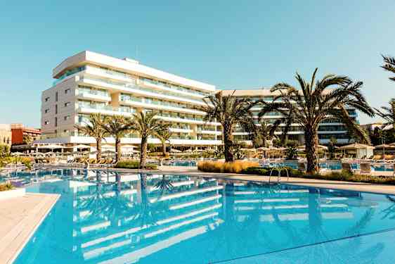 Hotell med basseng og palmer i et solrikt område. (AI-generert tekst)