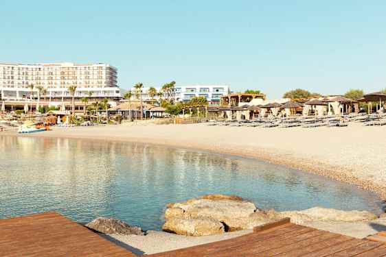 Strand med solsenger og parasoller, hotellbygninger i bakgrunnen. (AI-generert tekst)