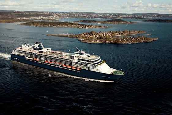 Et cruiseskip seiler på en blå sjø med øyer i bakgrunnen. (AI-generert tekst)
