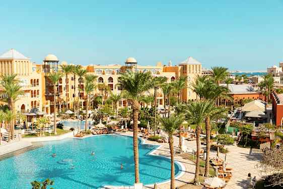 Hotellområde med basseng og palmer. (AI-generert tekst)