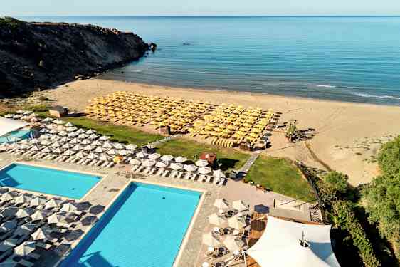 Hotellbasseng og solsenger nær sandstrand med havutsikt. (AI-generert tekst)