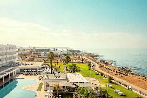 Bilde som viser et hotellområde med basseng og grøntområder nær sjøen. (AI-generert tekst)