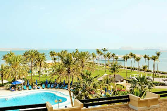 Bilde av en strandresort med basseng, palmer og havutsikt. (AI-generert tekst)