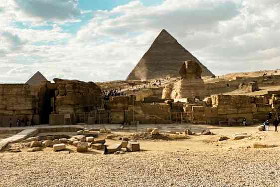 Steinete område med pyramider og sfinksen under en klar himmel. (AI-generert tekst)