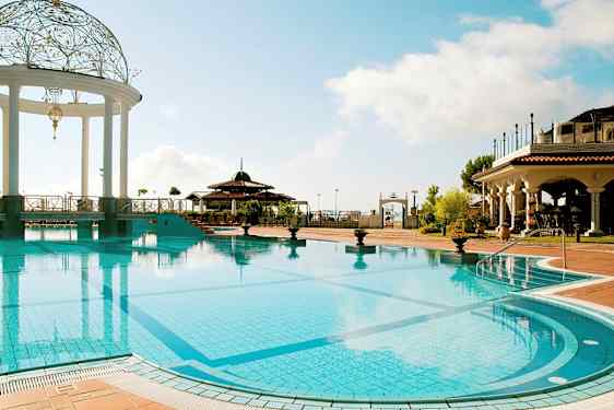 Et utendørsbasseng med en dekorert paviljong og omgivelser med bygninger i middelhavsstil. (AI-generert tekst)
