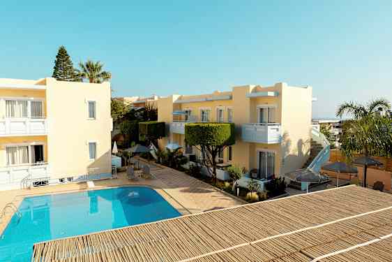 Gule bygninger rundt et basseng med utemøbler og parasoller. (AI-generert tekst)