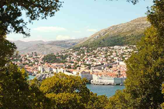 En utsikt over Dubrovnik med sin historiske bymur, omgitt av grøntområder. (AI-generert tekst)