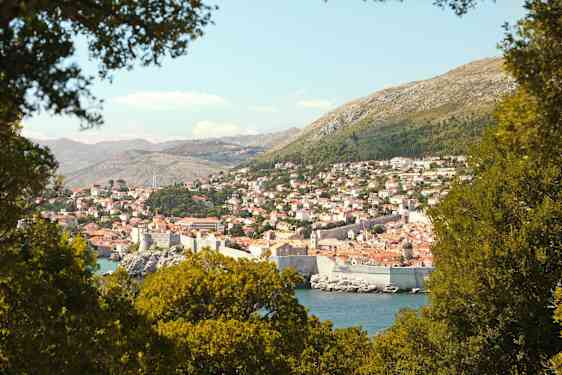 En utsikt over Dubrovnik med sin historiske bymur, omgitt av grøntområder. (AI-generert tekst)