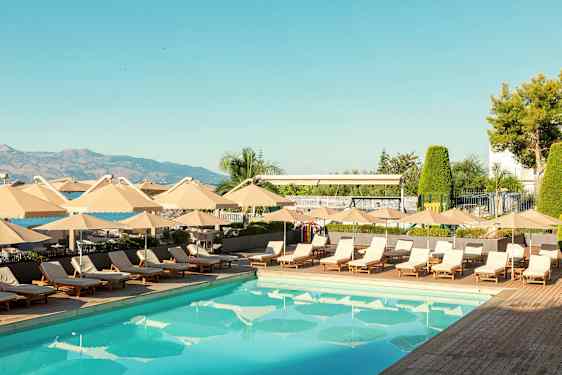 Et utendørs svømmebasseng omgitt av solsenger og parasoller. (AI-generert tekst)