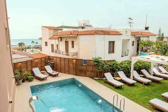 Utendørsbasseng med solsenger og omkringliggende bygninger i bakgrunnen. (AI-generert tekst)