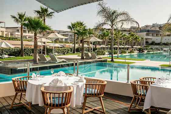 Et dekket bord ved et basseng på et hotellområde. (AI-generert tekst)